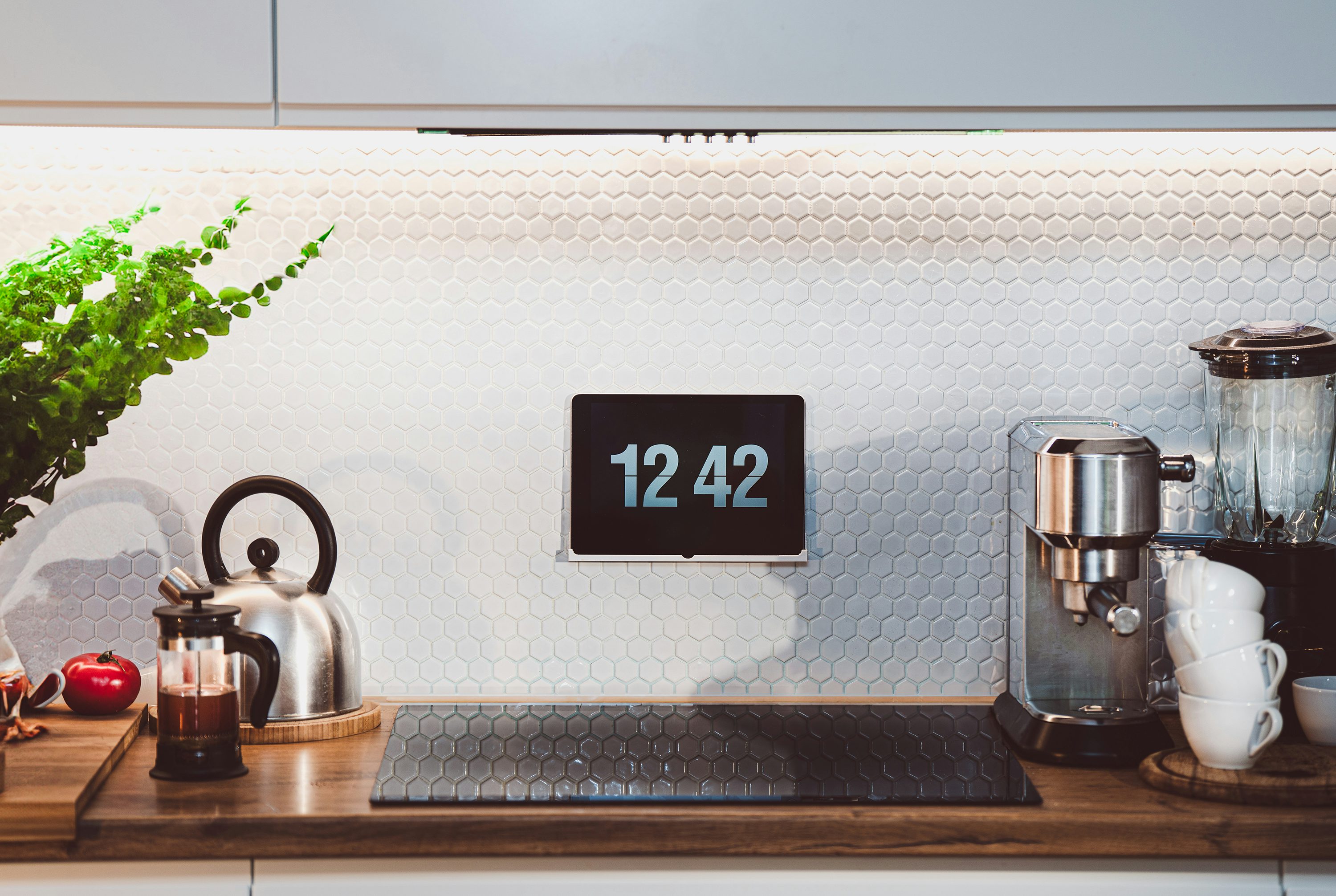 Smart display mounted in a modern kitchen with espresso machine and kettle